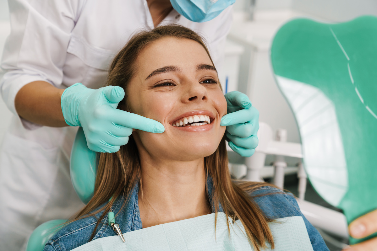 woman smiling while looking at mirror in dental clinic