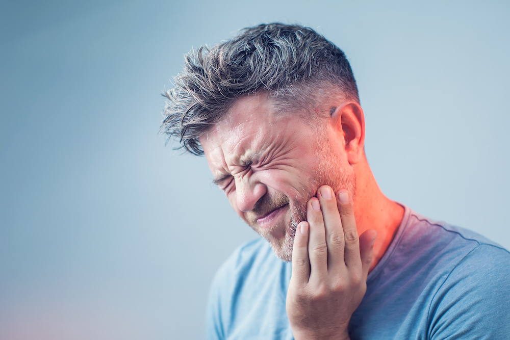 man showing tooth pain on the side of his mouth